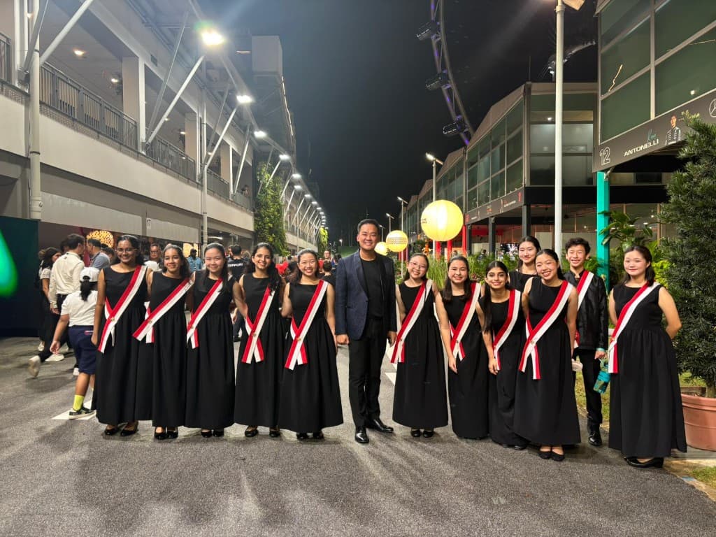 Singapore F1 evening: choir in formal black with sashes posing with conductor at the track venue